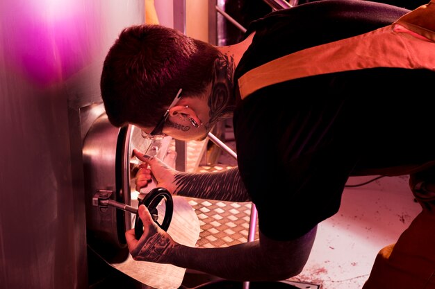 Homme aux tatouages produisant de la bière artisanale