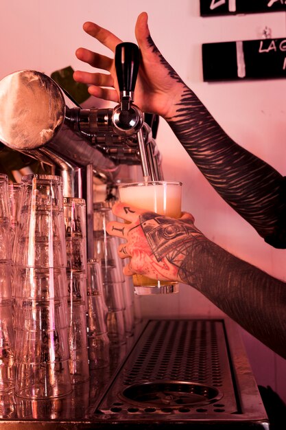 Homme aux tatouages produisant de la bière artisanale