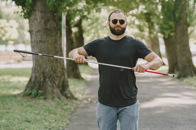 Homme aveugle. Les personnes handicapées, les personnes handicapées et la vie quotidienne. Homme malvoyant avec bâton de marche, marches descendantes dans le parc de la ville.