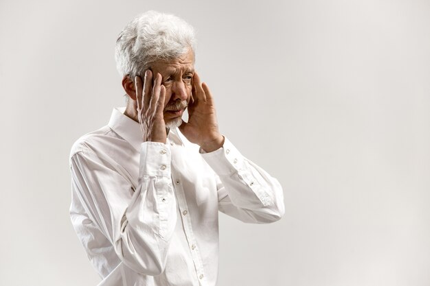 Homme ayant mal à la tête. Homme d'affaires debout avec stress isolé sur un mur blanc. Portrait d'homme demi-longueur. Émotions humaines, concept d'expression faciale