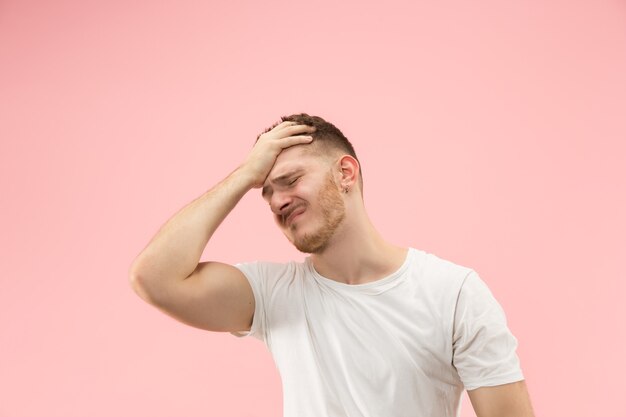 Homme ayant mal à la tête. Isolé sur fond rose.