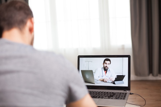 Homme ayant une vidéoconférence avec son médecin pendant l'auto-isolement.
