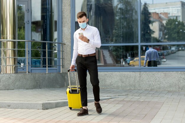 Homme avec des bagages portant un masque