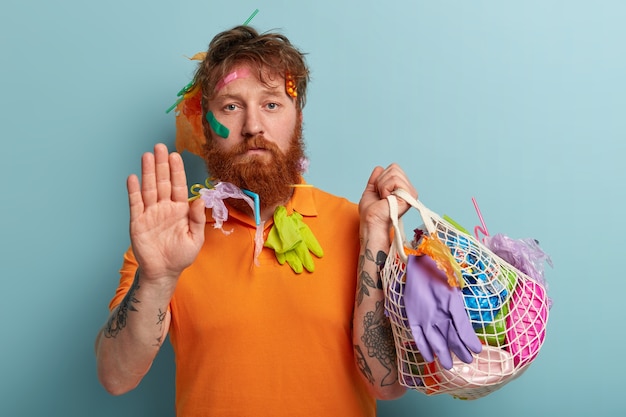 Homme avec barbe au gingembre tenant des sacs avec des déchets plastiques