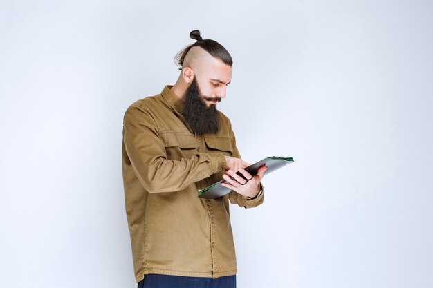 Homme à la barbe contrôlant les documents financiers.