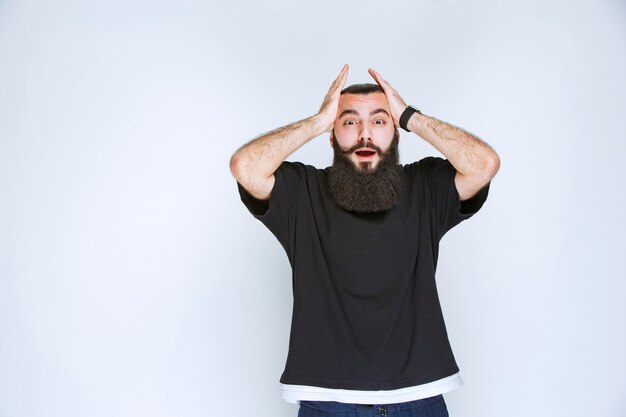 L'homme à la barbe devient extrêmement heureux à cause de quelque chose.