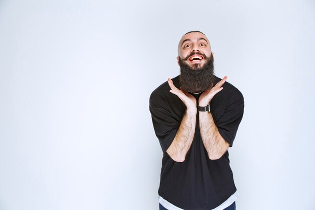 L'homme à la barbe devient extrêmement heureux à cause de quelque chose.