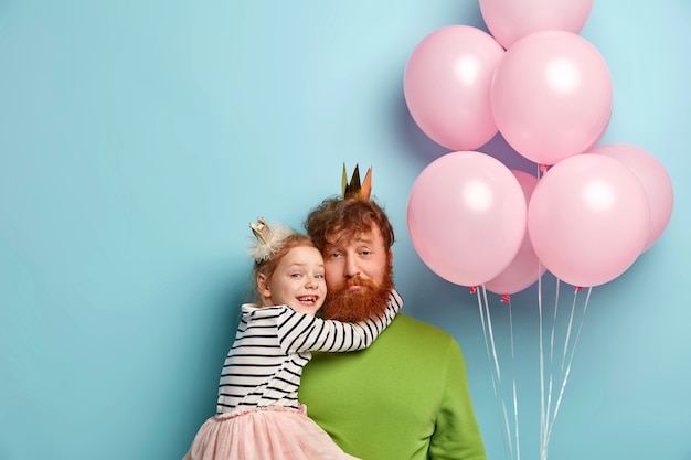 Homme à la barbe de gingembre et sa fille avec des accessoires de fête