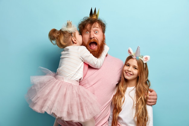 Photo gratuite homme à la barbe de gingembre et ses filles avec des accessoires de fête