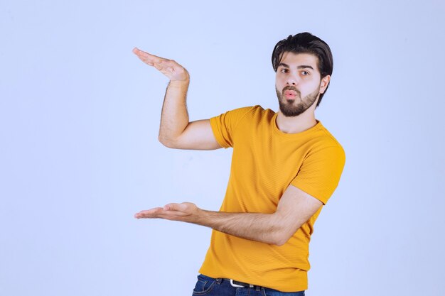 Homme à la barbe montrant les mesures estimées d'un objet.