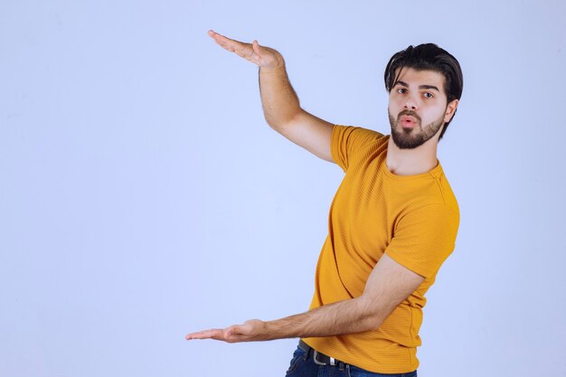 Homme à la barbe montrant les mesures estimées d'un objet.