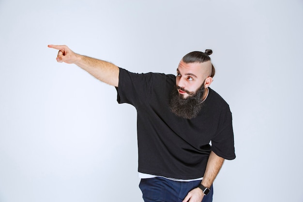 Photo gratuite homme à la barbe pointant du doigt quelqu'un autour.