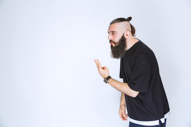 Homme à la barbe pointant du doigt quelqu'un autour.