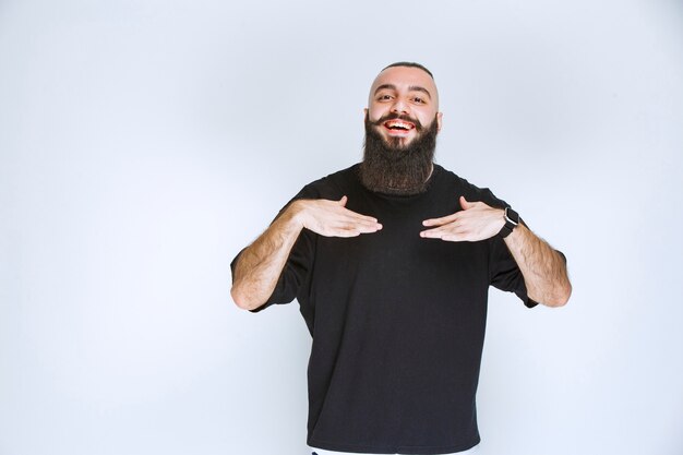 Homme à la barbe pointant sur lui-même.