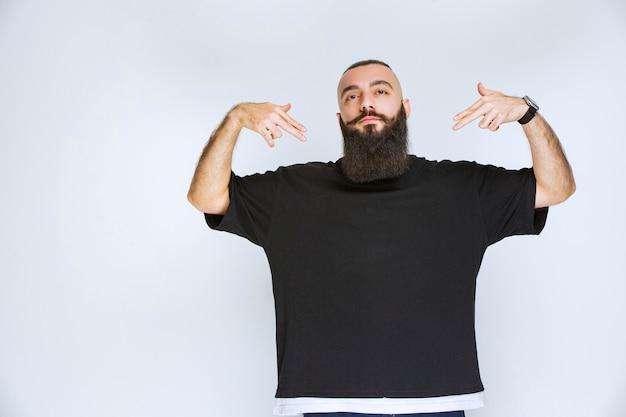 Homme à la barbe pointant sur lui-même.