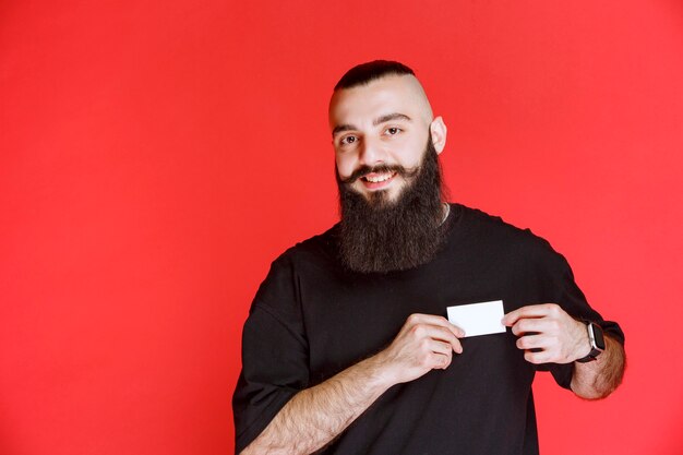Homme à la barbe présentant sa carte de visite.