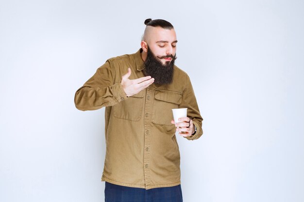 Homme à la barbe sentant son café.