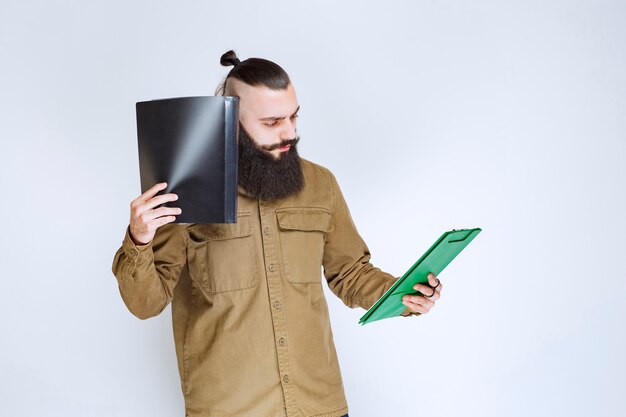 Homme à la barbe tenant un questionnaire et a l'air confus et réfléchi.