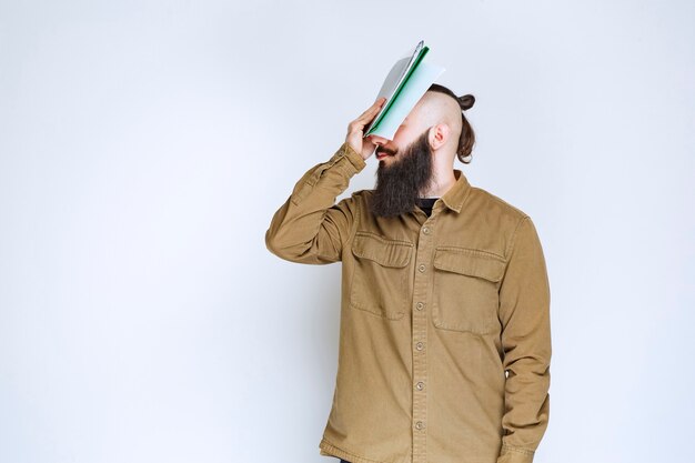 Homme à la barbe tenant un questionnaire et a l'air confus et réfléchi.