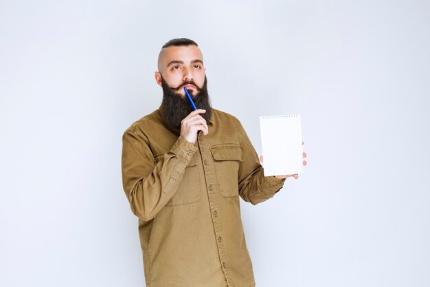 Homme à la barbe tenant un questionnaire et a l'air confus et réfléchi.