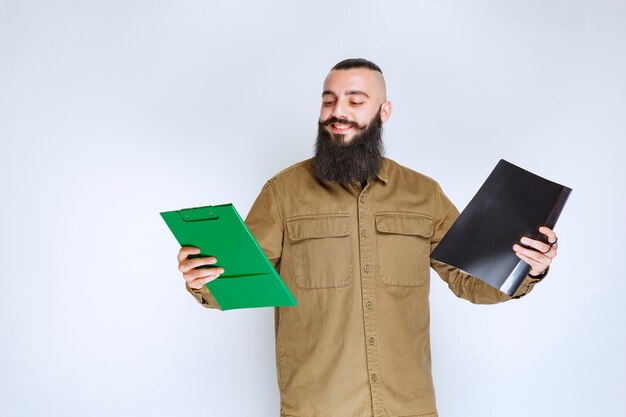 Homme à la barbe vérifiant deux projets différents pour choisir le gagnant.