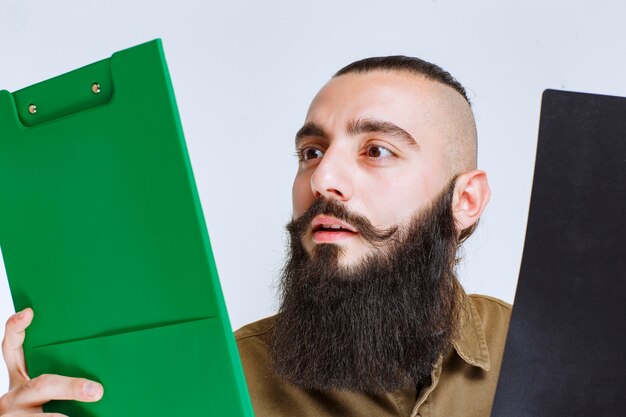 Homme à la barbe vérifiant deux projets différents pour choisir le gagnant.