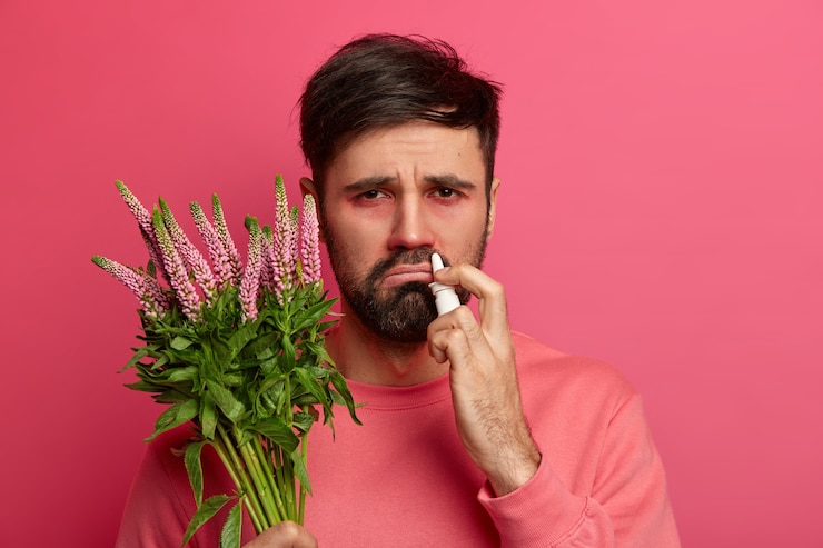 Photo gratuit un homme barbu allergique tient une plante, utilise des gouttes nasales pour soigner les éternuements, a déplu à l'expression du visage, a une réaction à l'allergène, guérit la maladie de la mer, suit les conseils de l'allergologue. concept de soins de santé