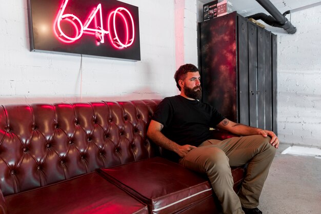 Homme barbu assis sur un canapé dans le salon de coiffure