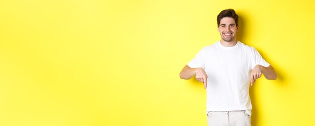 Homme barbu attirant pointant les doigts vers le bas montrant la bannière de l'événement debout sur fond jaune