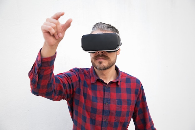 Homme barbu concentré dans le casque de réalité virtuelle