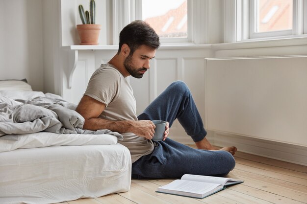 Homme barbu concentré détendu posant à la maison tout en travaillant