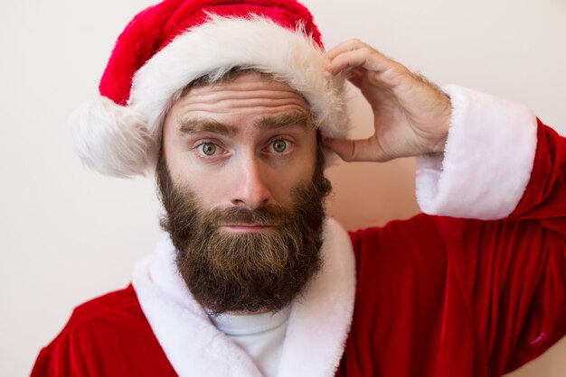 Homme barbu confus portant le costume du père Noël