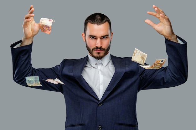 Homme barbu en costume détenant de l'argent comptant isolé sur fond gris.