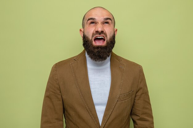 Homme barbu en costume marron jusqu'à crier avec une expression agressive