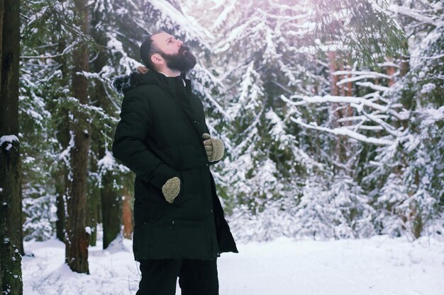 Homme barbu dans les bois d'hiver. séduisant jeune homme heureux avec barbe à pied dans le parc.