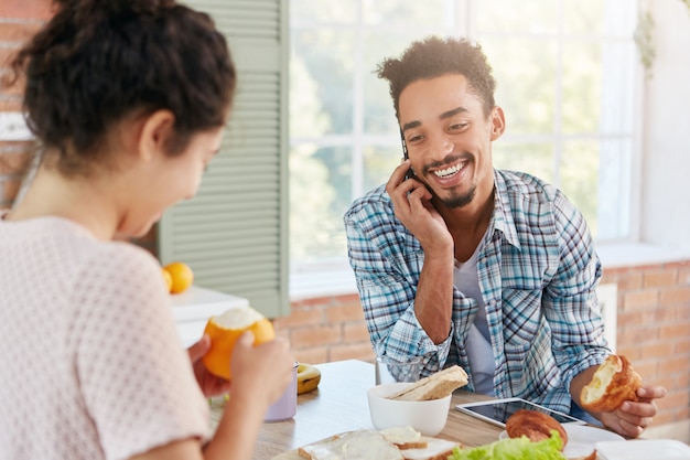 Homme barbu élégant à la recherche agréable parle au téléphone intelligent