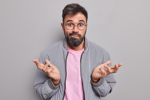 Un homme barbu ignorant haussant les épaules a l'air perplexe et inconscient dit que je ne comprends pas