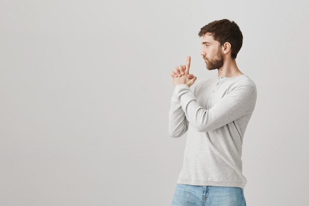 Homme barbu impertinent agissant comme un agent secret avec une arme à feu