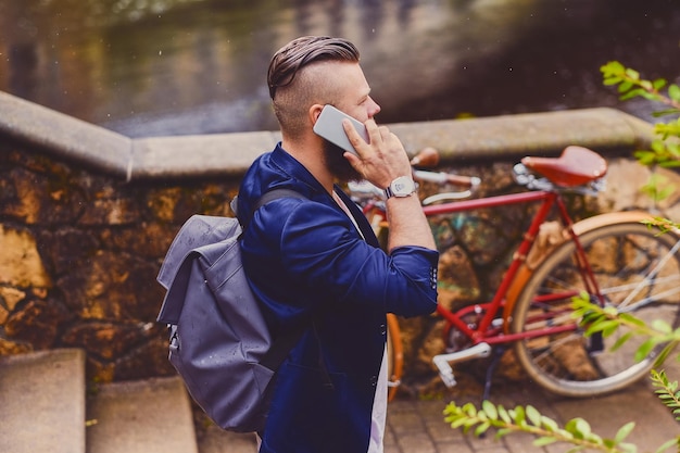 Un homme barbu occasionnel dans un parc parle par téléphone intelligent.