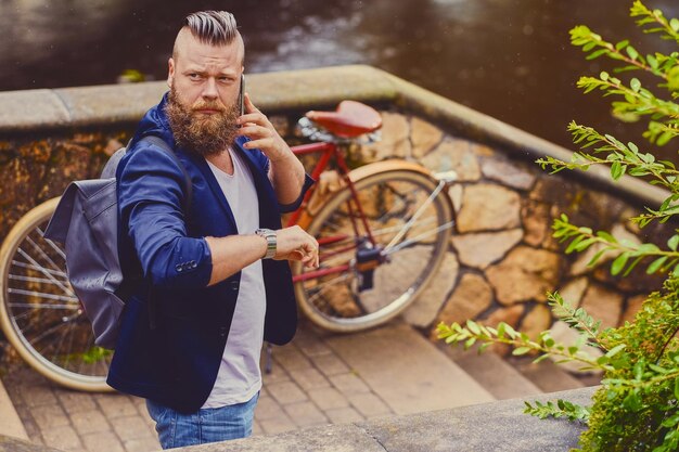 Un homme barbu occasionnel dans un parc parle par téléphone intelligent.