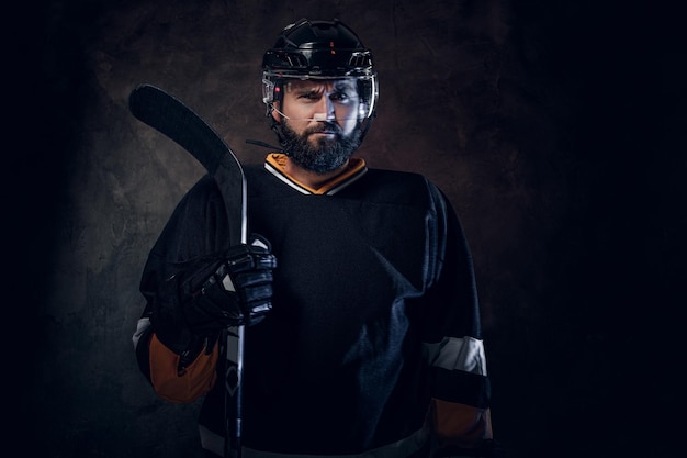 Un homme barbu professionnel en tenue de joueur de hockey pose pour le photographe.