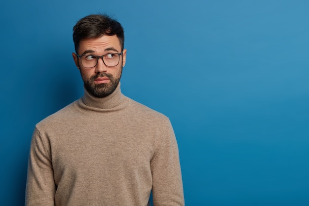 Homme barbu réfléchi concentré au-dessus avec une expression inconsciente