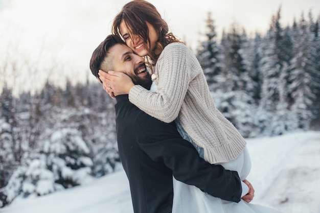 Homme barbu et sa belle épouse posent sur la neige dans une forêt d&#39;hiver magique