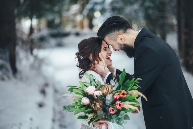 Homme barbu et sa belle épouse posent sur la neige dans une forêt d&#39;hiver magique