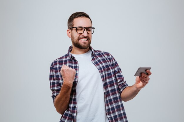 Homme barbu si heureux dans des lunettes avec smartphone