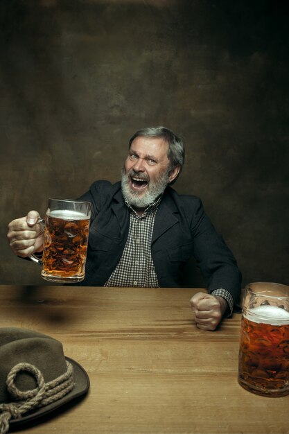 Homme barbu souriant, boire de la bière dans un pub