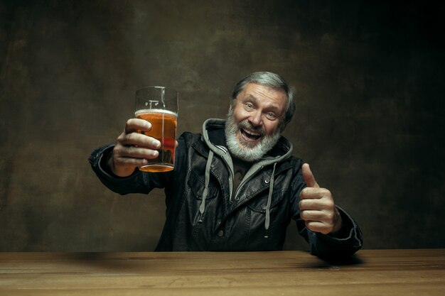 Homme barbu souriant, boire de la bière dans un pub