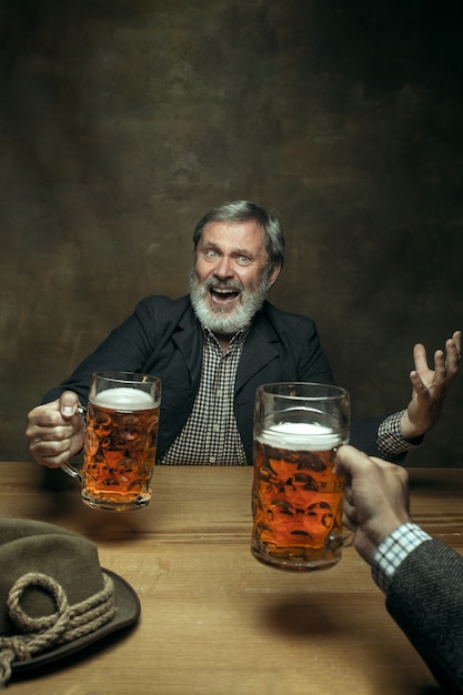 Homme barbu souriant, boire de la bière dans un pub