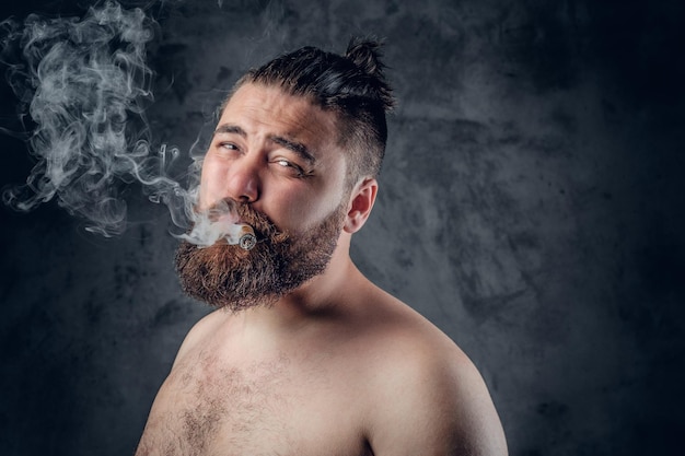 Photo gratuite homme barbu torse nu drôle fumant un cigare sur fond gris.