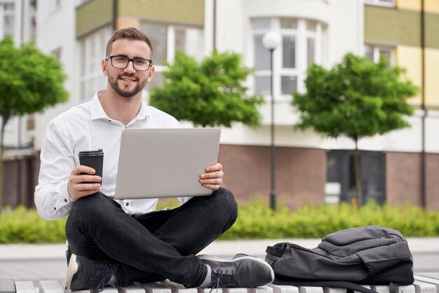 Homme barbu travaillant assis sur un banc avec les jambes croisées